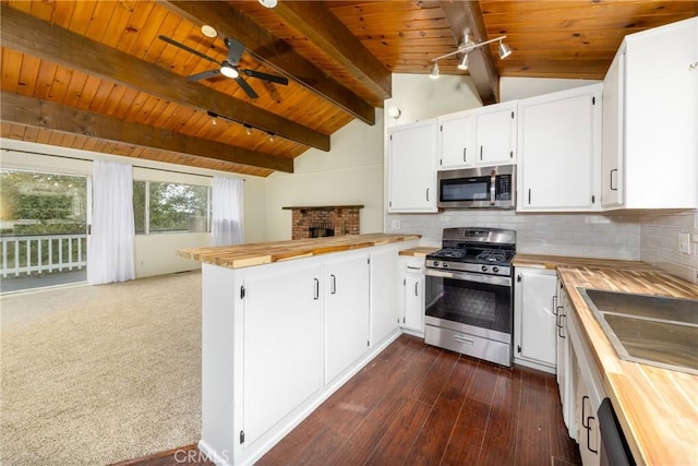 kitchen featuring vaulted ceiling with beams, a peninsula, a ceiling fan, wooden counters, and appliances with stainless steel finishes