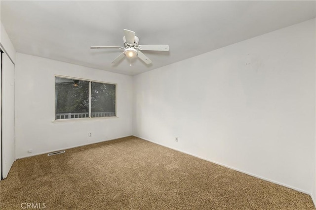 unfurnished room featuring visible vents, carpet floors, and ceiling fan