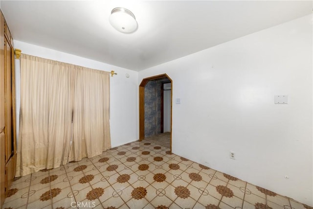 spare room featuring arched walkways and light floors