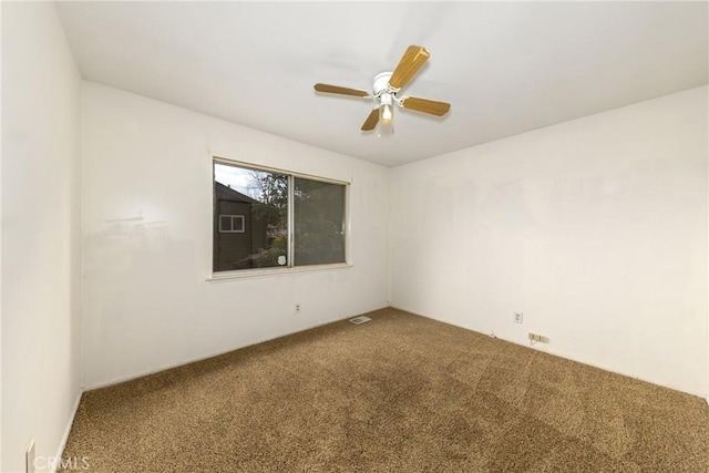 carpeted spare room with visible vents and ceiling fan