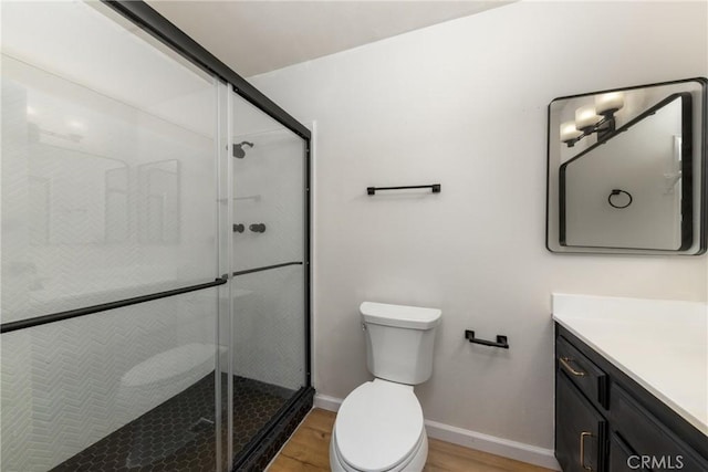 full bath featuring a stall shower, toilet, vanity, and wood finished floors