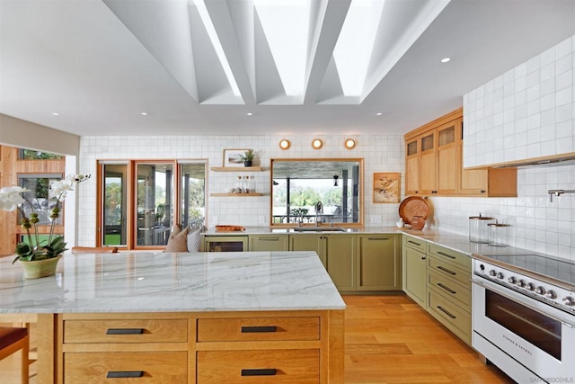 kitchen featuring a skylight, backsplash, green cabinets, electric range, and light stone countertops