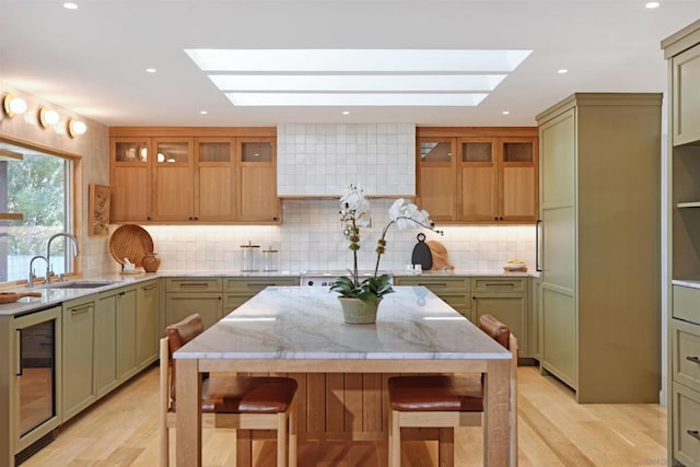 kitchen featuring light stone countertops, a center island, green cabinets, and a skylight