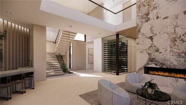 wine room with hardwood / wood-style floors, a high end fireplace, and a high ceiling