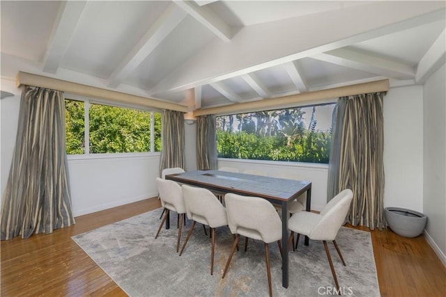 dining space with hardwood / wood-style flooring and lofted ceiling with beams