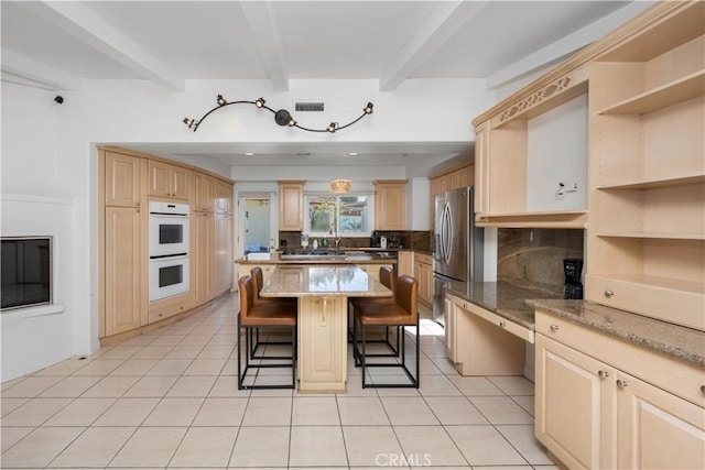 kitchen featuring stainless steel fridge, a breakfast bar area, a kitchen island, light brown cabinetry, and beamed ceiling