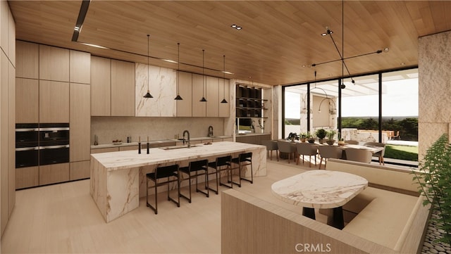 kitchen featuring wood ceiling, backsplash, an island with sink, decorative light fixtures, and light wood-type flooring