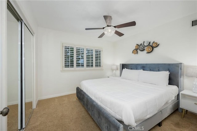 bedroom with light colored carpet, ceiling fan, and a closet