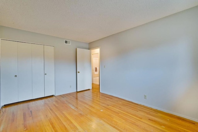 unfurnished bedroom with a closet, a textured ceiling, and light wood-type flooring