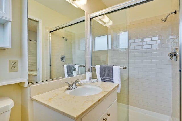 bathroom with vanity, a shower with door, and toilet