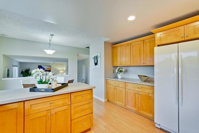 kitchen featuring pendant lighting, a textured ceiling, white fridge, and light hardwood / wood-style flooring