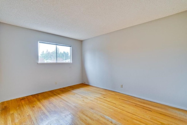 empty room featuring a textured ceiling and light hardwood / wood-style floors