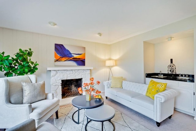 carpeted living room featuring sink and a fireplace