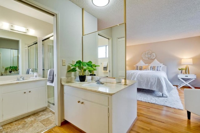 bathroom with vanity, an enclosed shower, hardwood / wood-style floors, and a textured ceiling