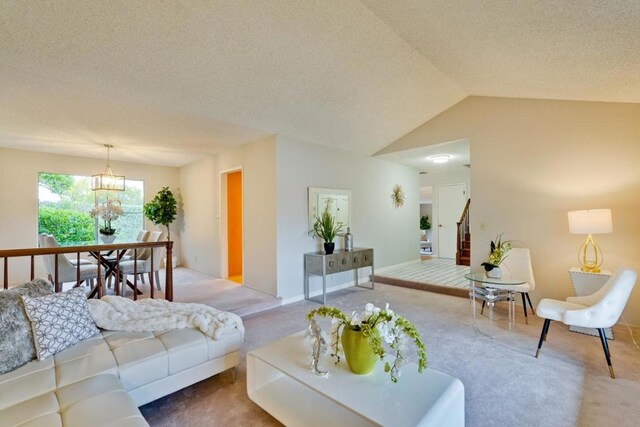 carpeted living room featuring a notable chandelier, vaulted ceiling, and a textured ceiling