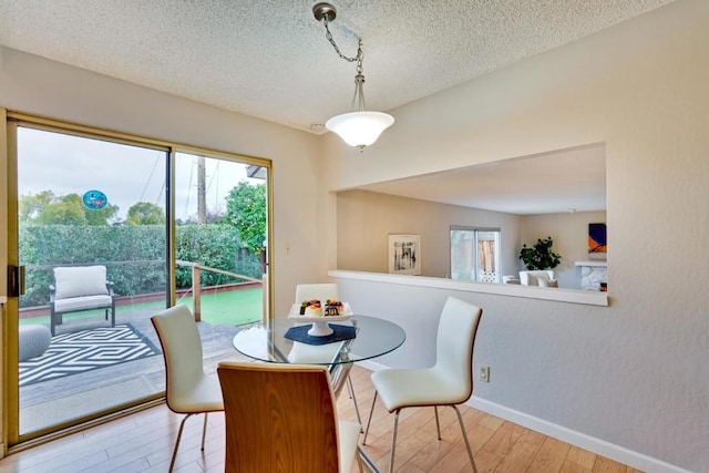 dining space featuring a textured ceiling and light wood-type flooring