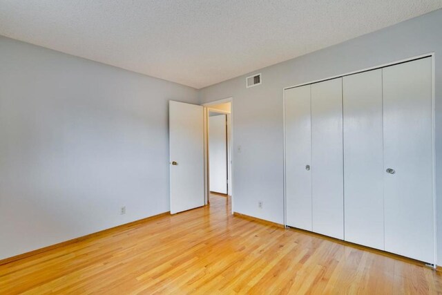 unfurnished bedroom featuring light hardwood / wood-style flooring, a closet, and a textured ceiling