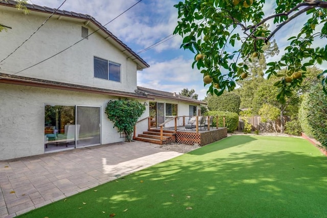 back of house featuring a wooden deck and a patio area