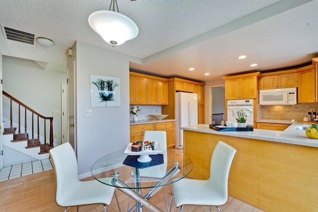 dining room with sink, a textured ceiling, and light wood-type flooring