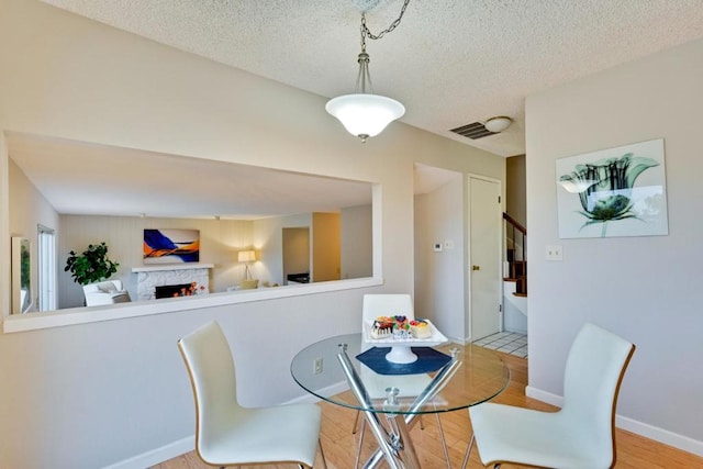 dining room featuring a fireplace, light hardwood / wood-style floors, and a textured ceiling