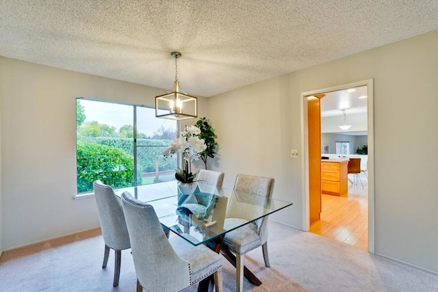 dining space with light carpet, a notable chandelier, and a textured ceiling