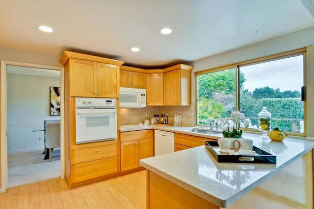 kitchen featuring sink, tasteful backsplash, light hardwood / wood-style flooring, light brown cabinets, and white appliances