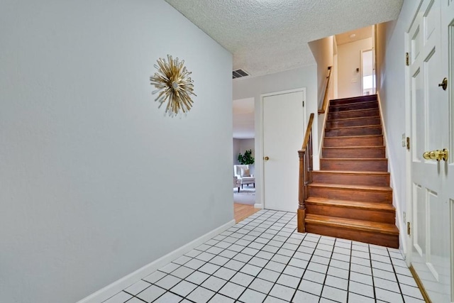 staircase with tile patterned flooring and a textured ceiling