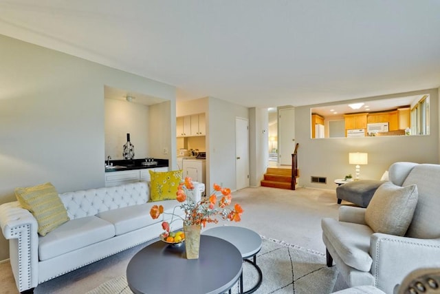 living room with washer and clothes dryer and light carpet