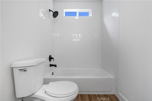 bathroom with tiled shower / bath combo, wood-type flooring, and toilet