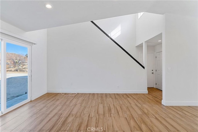 unfurnished living room with a towering ceiling and light hardwood / wood-style floors