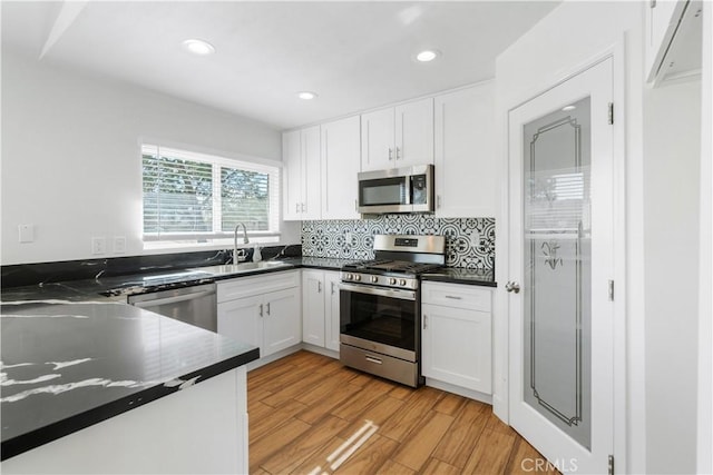 kitchen featuring stainless steel appliances, sink, white cabinets, and light hardwood / wood-style flooring