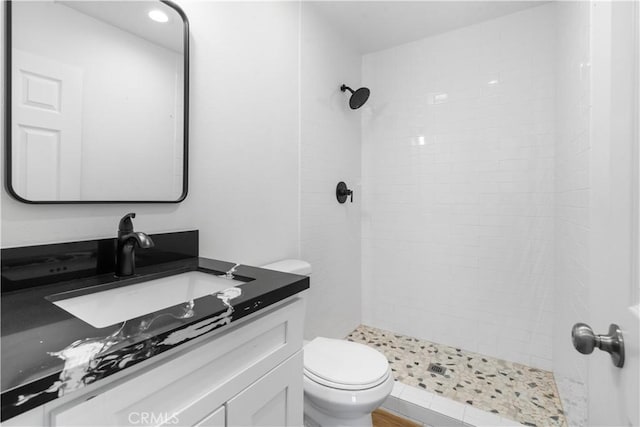 bathroom featuring tiled shower, vanity, and toilet