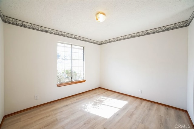 spare room featuring a textured ceiling and light hardwood / wood-style floors