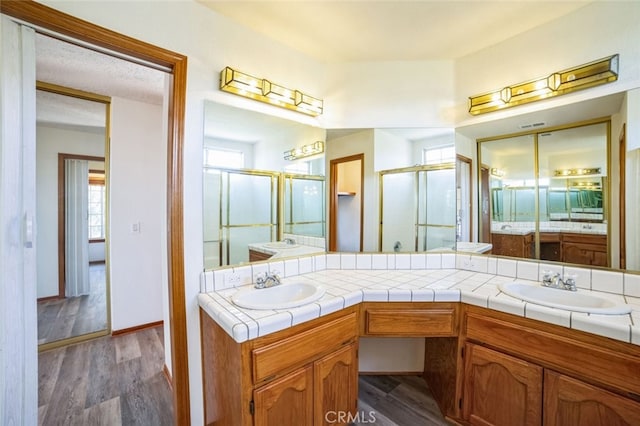 bathroom with wood-type flooring, an enclosed shower, and vanity