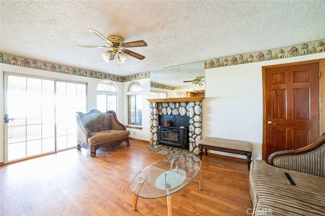 living room featuring a textured ceiling, wood-type flooring, and ceiling fan