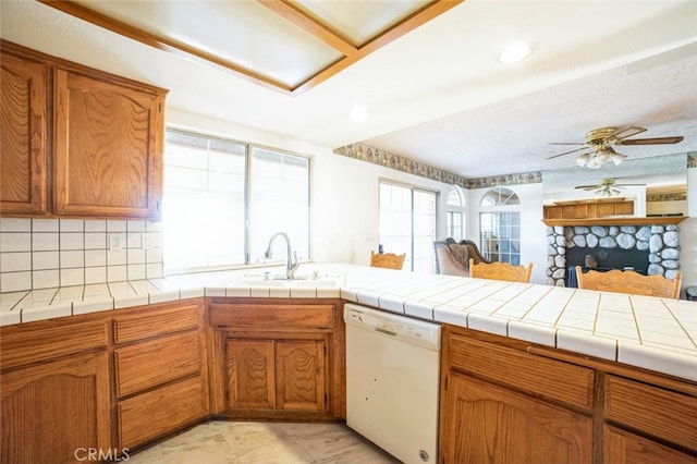 kitchen with sink, white dishwasher, tasteful backsplash, tile countertops, and kitchen peninsula