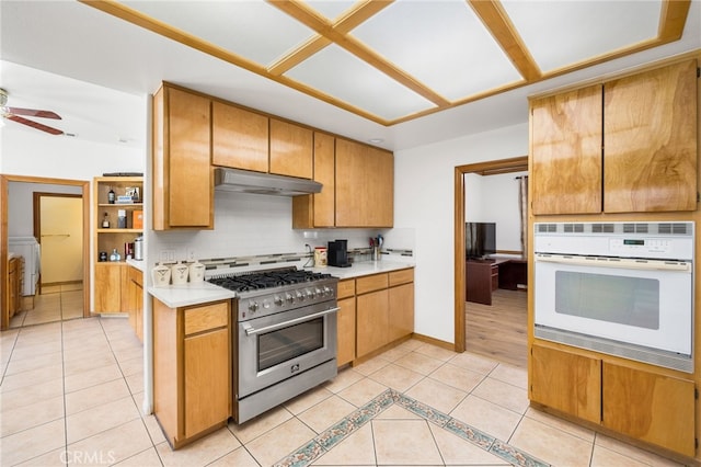 kitchen featuring light tile patterned floors, high end stainless steel range oven, washer / dryer, decorative backsplash, and oven