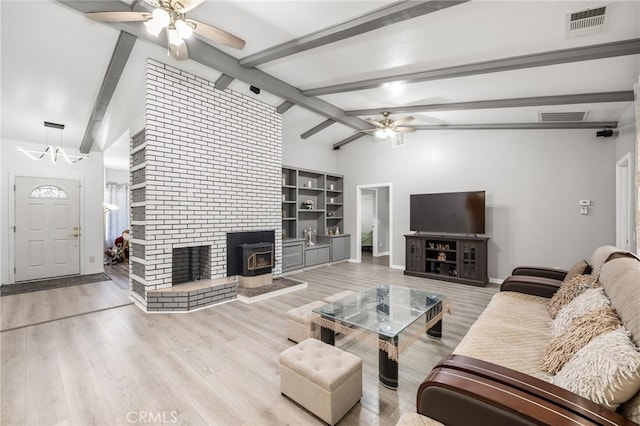 living room featuring light hardwood / wood-style flooring, lofted ceiling with beams, ceiling fan, and a wood stove