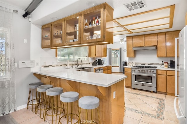 kitchen featuring stainless steel appliances, light tile patterned flooring, sink, and kitchen peninsula