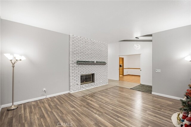 unfurnished living room with a brick fireplace and wood-type flooring