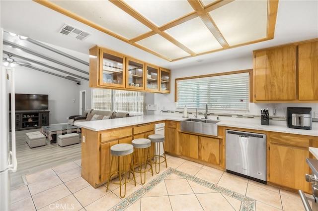 kitchen with sink, light tile patterned floors, stainless steel dishwasher, and kitchen peninsula