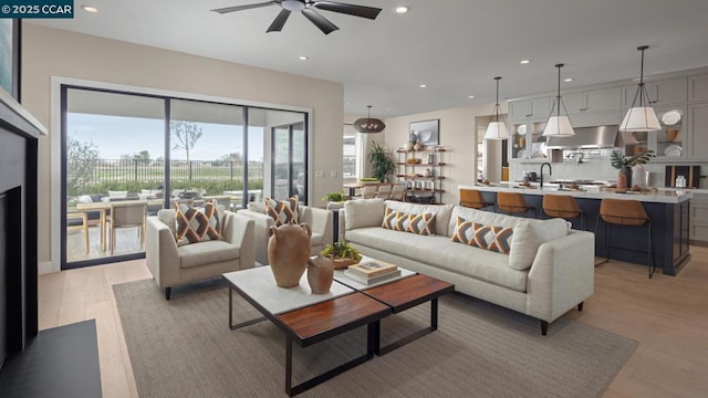 living room with ceiling fan, sink, and light hardwood / wood-style flooring