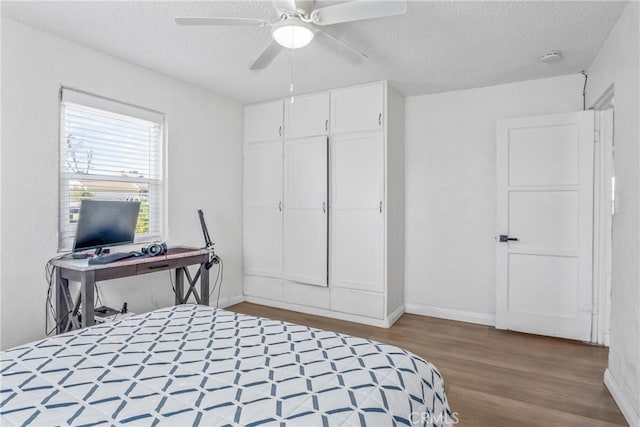 bedroom featuring ceiling fan, wood-type flooring, a closet, and a textured ceiling