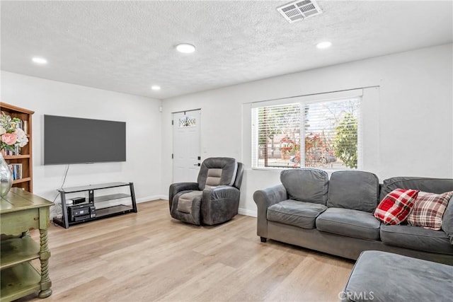 living room featuring a textured ceiling and light hardwood / wood-style flooring