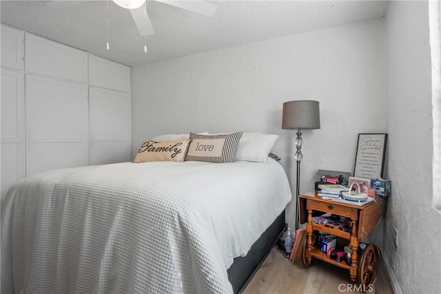 bedroom with ceiling fan, a textured ceiling, light wood-type flooring, and a closet