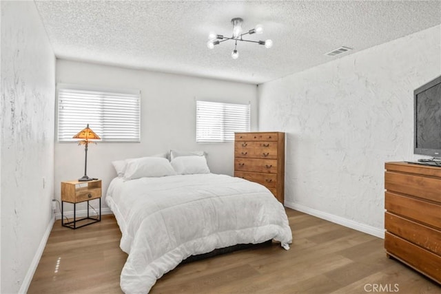 bedroom featuring hardwood / wood-style flooring, a chandelier, and a textured ceiling