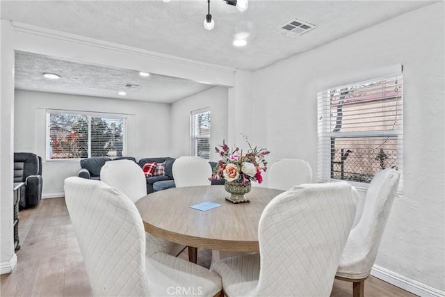 dining room with hardwood / wood-style floors and a textured ceiling