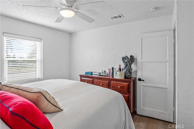 bedroom with ceiling fan, hardwood / wood-style floors, and a textured ceiling