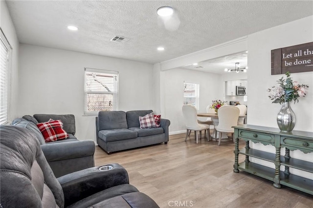 living room with a chandelier, light hardwood / wood-style flooring, and a textured ceiling