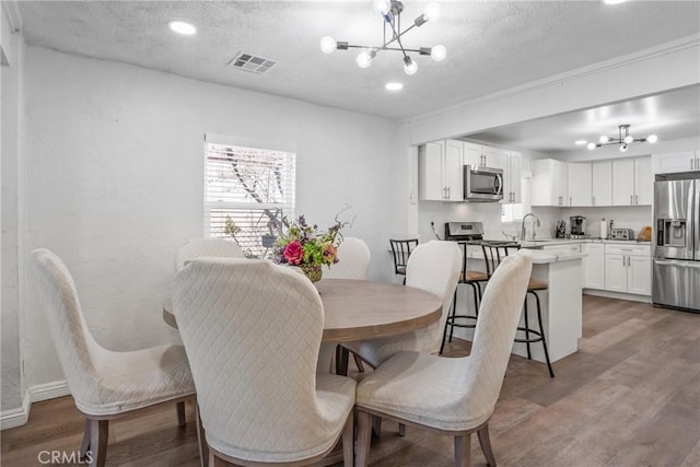 dining space featuring hardwood / wood-style floors, a textured ceiling, and a notable chandelier